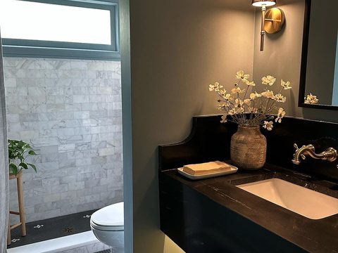 Elegant powder bathroom remodel with marble shower, brass fixtures, black vanity, and patterned tile floor in Ocala, FL - CBC Construction Group