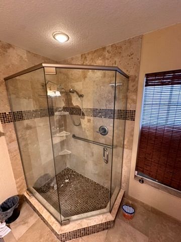 Custom corner shower with travertine tile and glass enclosure in Ocala, FL - CBC Construction Group bathroom renovation