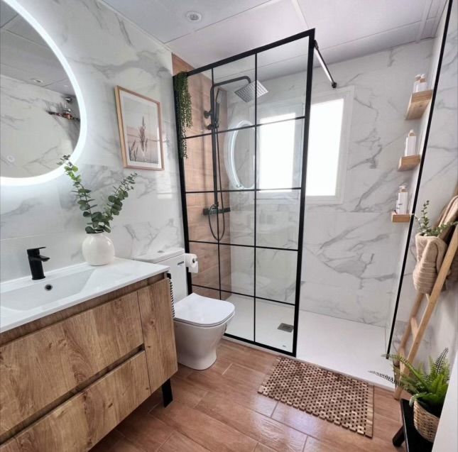 Modern spa bathroom with marble tile, wood vanity, and industrial shower glass in Ocala, FL - CBC Construction Group